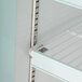 A white shelf with metal bars inside an Avantco glass door freezer.