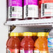 A group of bottles of juice on a shelf inside an Avantco swing glass door refrigerator.