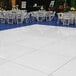 A white Palmer Snyder portable dance floor set up with tables and chairs.