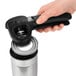 A person using a black OXO handheld can opener to open a can.