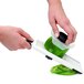 A hand using the OXO handheld mandoline slicer to cut a green bell pepper.