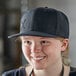 A woman wearing a black Mercer Culinary snapback hat with a small black logo.