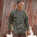 A man wearing an Uncommon Chef Orleans long sleeve chef coat in an outdoor catering setup smiles.