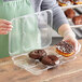 A hand holding a Polar Pak plastic tray with a chocolate frosted donut in it.