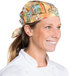 A smiling woman wearing an Intedge Coffee & Tea patterned chef neckerchief in a professional kitchen.