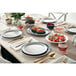 An oval white American Metalcraft linen melamine platter on a table set with plates, bowls, and forks.