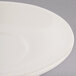 A close up of a Tuxton Reno eggshell white saucer with a rim.
