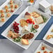 A white rectangular melamine platter stacked with food on a table.