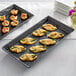An American Metalcraft black faux slate rectangular melamine platter with a variety of appetizers on a table.