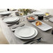 A Mix & Matte marble white American Metalcraft melamine plate on a table with silverware and a glass of wine.