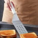 A person using a Dexter-Russell perforated turner to lift a piece of toast.