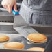A person using a Dexter-Russell Cool Blue Basics solid turner with a blue handle to cut a pancake.