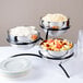 A Vollrath metal display stand with three staggered metal trays holding bowls of food.