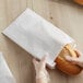 A person in gloves holding a loaf of bread in a Bagcraft Packaging white bread bag.