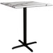 A Lancaster Table & Seating bar height table with a white marble top and black cross base.