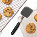 An OXO silicone cookie spatula next to a cookie on a cooling rack.