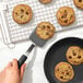 A hand holding an OXO black silicone cookie spatula over cookies on a pan.