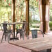 A Lancaster Table & Seating rectangular table with a textured wood finish on an outdoor patio with chairs.