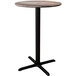 A Lancaster Table & Seating Excalibur round bar height table with a textured mixed plank finish and a black cross base.