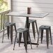 A Lancaster Table & Seating rectangular counter height table with a textured finish on a patio with stools.