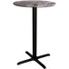 A Lancaster Table & Seating bar table with a round marble top and black cross base.