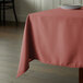 A square table with a mauve Intedge tablecloth on it.