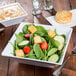 A white Siciliano square melamine bowl filled with salad with croutons and cucumbers.