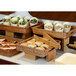 A hotel buffet with a variety of food items displayed on bamboo L-shaped risers.