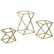 A Front of the House Twist 3-piece matte brass stainless steel riser set with geometric metal frames in gold.