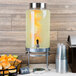 A Cal-Mil glass beverage dispenser with liquid and fruit in it.