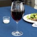 A Libbey wine glass filled with red wine on a table.