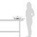 A woman standing next to a table with a Vollrath stainless steel round food pan in it.