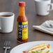 A bottle of Old Bay hot sauce on a table next to a plate of food.