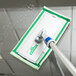 An Unger indoor window cleaning kit mop with a green handle on a glass surface.