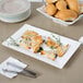 A CAC bone white rectangular porcelain platter with bread and cheese triangles on it.