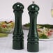 A Chef Specialties forest green pepper mill and salt shaker on a table.