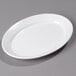 A white oval Carlisle Dallas Ware platter on a gray surface.