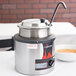 A Vollrath round soup warmer with a lid on top filled with soup.