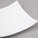 An Arcoroc white porcelain square plate with curved edges.