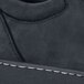 A close up of a black MOZO soft toe sneaker with white stitching.