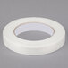 A roll of Shurtape white fiberglass reinforced strapping tape on a gray surface.