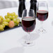 Two Stolzle INAO wine glasses filled with red wine on a table.