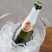 A Fineline disposable plastic wine/champagne chiller filled with ice holding a bottle of champagne.