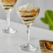 Two Acopa Empire martini glasses filled with dessert topped with whipped cream and fruit.