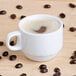 A white Tuxton espresso cup filled with coffee with a heart shape on top.