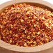 A bowl of Regal Mild Crushed Red Pepper on a wooden table.
