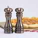 A Chef Specialties burnished copper pepper mill and salt shaker next to a pizza.