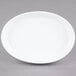 A white oval porcelain serving platter with a white rim on a gray surface.