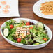 A salad with grilled chicken and shrimp on a CAC porcelain oval platter.