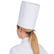 A woman wearing a white Royal Paper pleated disposable chef hat.